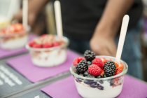 Fila di porzioni di macedonia di frutta con bacche e yogurt — Foto stock