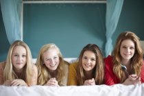 Portrait of four teenage girls lying on bed — Stock Photo