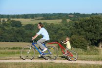 Padre e hijo en bicicleta en los campos - foto de stock