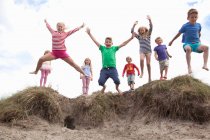 Kindergruppe springt von Sanddünen, Wales, Großbritannien — Stockfoto