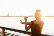 Giovane jogger femminile sul lungofiume guardando il lettore MP3 — Foto stock