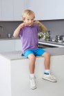 Junge sitzt mit Karottenschnurrbart auf Seite in Küche — Stockfoto