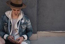 Junger Mann lehnt mit Smartphone an Wand — Stockfoto