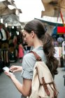 Молода жінка текстових повідомлень на мобільний телефон, ринку Сан-Лоренцо, Флоренції, Тоскана, Італія — стокове фото