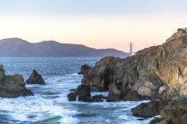 Rocky shore with mountain range and Golden Gate bridge — Stock Photo