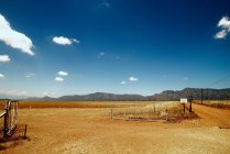 Паркан в сухому сільському ландшафті з яскравим блакитним небом — стокове фото