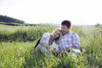 Зрелая пара, сидящая в поле — стоковое фото