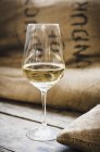 Glas Weißwein auf Holz mit Sack — Stockfoto