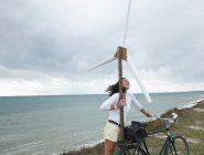 Donna con turbina eolica al mare — Foto stock