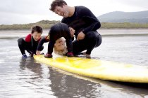 Father and sons playing with surfboard — Stock Photo