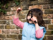 Girl looking at worm with magnifying glass — Stock Photo