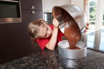 Menina derramando mistura de bolo em lata de bolo — Fotografia de Stock