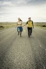 Ретро-стилі молоді пара біг взявшись за руки на дорозі, коді, Вайомінг, США — стокове фото