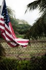 American flag hanging by chain fence — Stock Photo