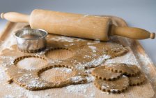 Raw cookies with dough and rolling pin — Stock Photo