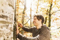 Mann ritzt mit Taschenmesser in Baumstamm — Stockfoto