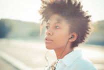 Портрет задумчивой молодой женщины, слушающей наушники — стоковое фото