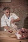 Мясник режет мясо в магазине — стоковое фото