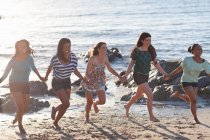 Женщины держатся за руки на пляже — стоковое фото