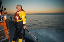 Portrait of mature man holding lifeboat railing at sea — Stock Photo