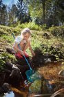 Menina pesca com rede em riacho — Fotografia de Stock