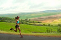 Jovem mulher correndo na paisagem de Palouse Hills, Washington, EUA — Fotografia de Stock