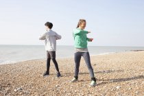 Man and woman training, twisting on Brighton beach — Stock Photo