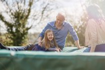 Happy family sitting on trampoline together — Stock Photo