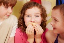 Girl eating party food, friends watching — Stock Photo