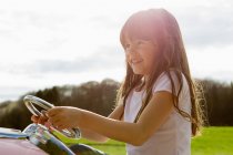 Девушка за рулем игрушечного самолета в поле — стоковое фото