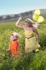 Schwestern spielen im Blumenfeld — Stockfoto