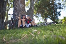 Cyclists resting by tree — Stock Photo
