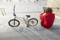 Rear view of man sitting on steps with BMX and using smartphone — Stock Photo
