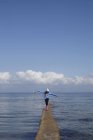 Mädchen läuft an schmalen Pier an der Küste entlang — Stockfoto