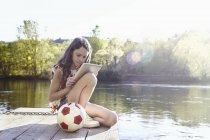 Дівчина-підліток з м'ячем використовує цифровий планшет на дерев'яному джуті — стокове фото
