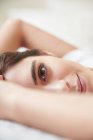Close up portrait of beautiful young woman lying on bed — Stock Photo