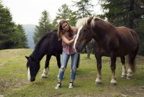 Giovane donna che accarezza i cavalli palomini in collina, Sattelbergalm, Tirolo, Austria — Foto stock