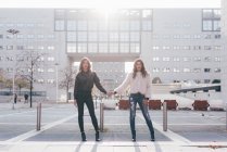 Portrait of twin sisters, in urban area, side by side, holding hands — Stock Photo