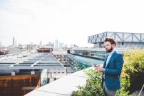 Молодий бізнесмен дивиться з офісної тераси на даху — стокове фото
