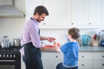 Pai e filho preparando comida em casa — Fotografia de Stock
