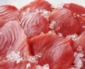 Raw sliced tuna steaks with crushed ice — Stock Photo