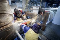 Trabajadores moliendo tubería en central eléctrica de gas - foto de stock