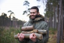 Молодой человек собирает дрова для костра в лесу — стоковое фото