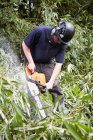 Travailleur utilisant une tronçonneuse dans la forêt — Photo de stock