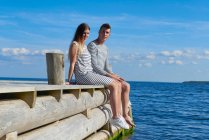 Young couple sitting on wooden pier, relaxing — Stock Photo