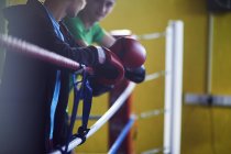 Boxeadores masculinos jóvenes apoyados en cuerdas de anillo de boxeo - foto de stock