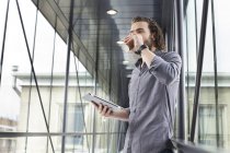 Mann mit digitalem Tablet auf Kaffeepause in modernem Gebäude — Stockfoto