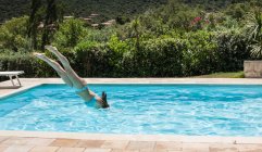 Mujer joven zambulléndose en la piscina, Capoterra, Cerdeña, Italia - foto de stock