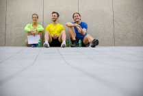 Três amigos sentados no chão vestindo roupas esportivas — Fotografia de Stock