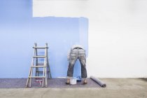 Rear view of man painting wall by blue color — Stock Photo